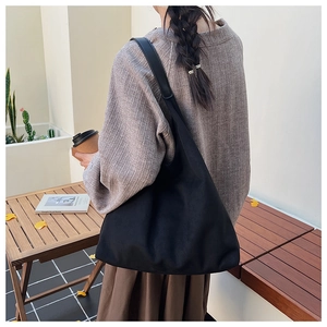 Large black suede tote bag shown on a wooden table in a cozy cafe setting