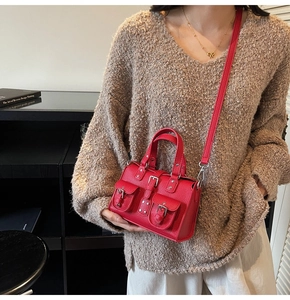 Close-up of red lychee pattern leather handbag with utility-style buckle pockets