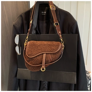 Detail of coffee plush saddle bag with leather trim and gold metal buckle on a blazer