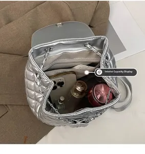 Interior capacity of silver quilted backpack showing phone, perfume and cosmetics