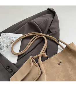 Dettaglio borsa tote retrò marrone chiaro con logo in metallo e pochette coordinata