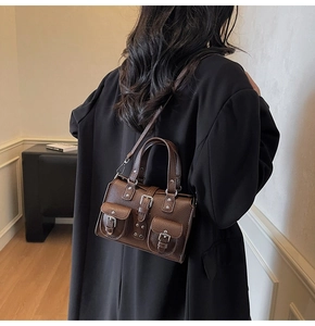 Close-up of retro brown lychee grain leather handbag with silver buckles and flap pockets