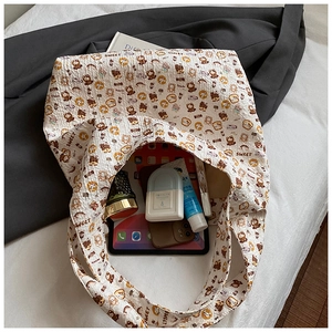 Detail of white tote bag interior with teddy bear prints holding tablet and cosmetics