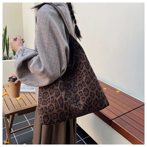 Detail of large leopard print tote bag featuring sturdy brown leather shoulder straps
