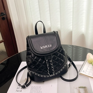 Close-up of quilted black leather backpack with silver metal logo and chain detail