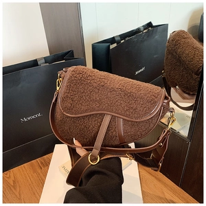 Close-up of deep brown plush saddle bag with premium leather trim and gold metal hardware