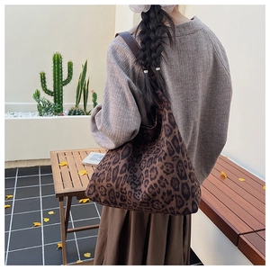 Detail of a large leopard print tote bag styled in a cozy autumn outdoor setting