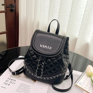 Close-up of black quilted backpack featuring silver chain details and embroidered logo