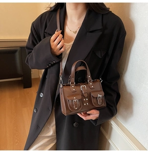 Detailed close-up of brown litchi pattern leather handbag with retro buckle pockets