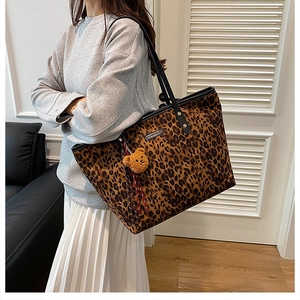 Detail der Totebag mit Leopardenmuster, Plüschbär-Anhänger und schwarzem Ledergriff