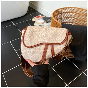 Detail of off-white faux fur saddle bag with brown leather trim and golden hardware