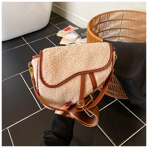 Detail showing plush faux shearling saddle bag with brown leather trim and golden D-buckle