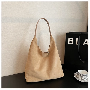 Detail view of large brown suede tote bag with slim handles in a lifestyle setting