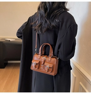 Brown litchi grain leather handbag showing adjustable shoulder strap on model's back