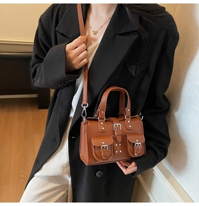 Close-up detail of brown litchi grain leather handbag with silver buckles and studs