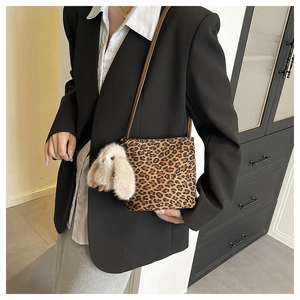 Dettaglio borsa a tracolla leopardata con ciondolo a coniglio soffice e blazer nero