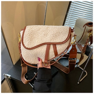 Detail of cream sherpa saddle bag with brown leather trim and golden metal hardware