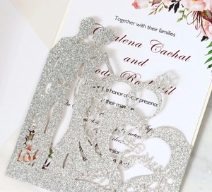Macro detail of silver glitter laser-cut wedding card with Mr & Mrs heart and ring design