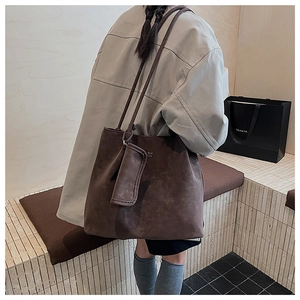 Dettaglio della borsa tote in pelle scamosciata marrone scuro con accessorio coordinato