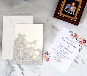 Close-up of laser-cut wedding invitation with silver glitter Mr & Mrs couple silhouette