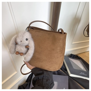Dettaglio borsa a secchiello marrone opaco con ciondolo a forma di coniglio peluche