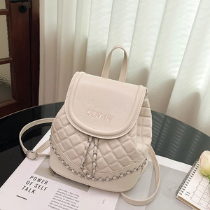 Close-up of quilted beige leather backpack with silver chain and WOMAN embroidery