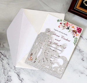 Detail of silver glitter laser cut wedding invitation with floral insert and white envelope