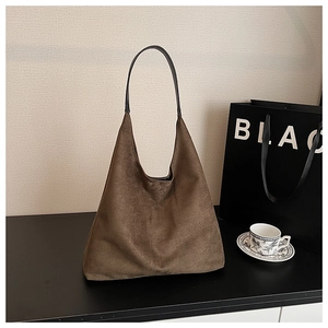 Detail of dark brown suede tote bag featuring a spacious hobo silhouette and black handles