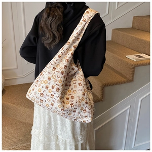 Detail view of white tote bag with cartoon bear patterns and wrinkled fabric texture