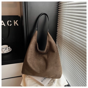 Detail of suede textured large brown tote bag with slim black straps in elegant setting