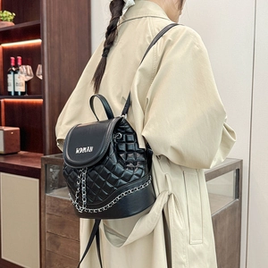 Detail showing quilted leather pattern and silver chain on a black bucket backpack