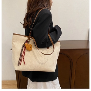 Beige Cord-Tasche mit braunem Lederbesatz und Plüschbär-Anhänger im Detail