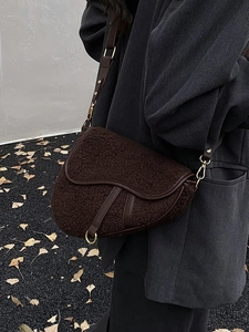 Chic brown shearling saddle bag with leather trim and gold hardware on model