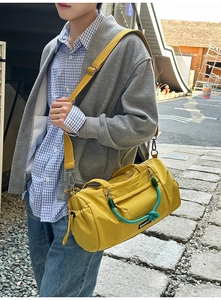 Detail der gelben Nylon-Zylindertasche mit kontrastierendem grünem Webgriff