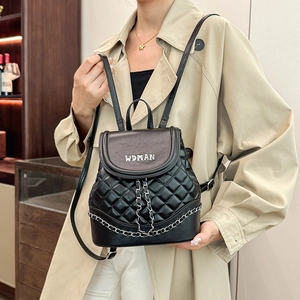 Detail of black quilted leather backpack featuring silver chain trim and metal lettering