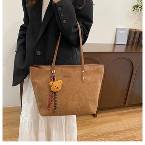 Detailansicht der braunen Cord-Tote-Bag mit Plüschbären-Anhänger und Ledergriffen