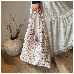 Close-up of a white canvas tote bag with brown bear patterns and Sweet letter printing