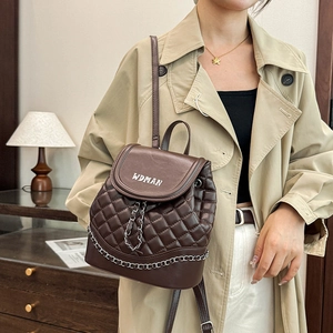 Detailed side view of dark brown quilted leather backpack featuring silver chain and logo