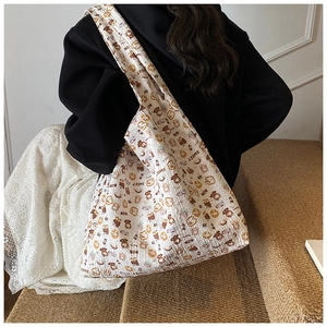 Detail of white tote bag with sweet cartoon bear pattern shown on model shoulder