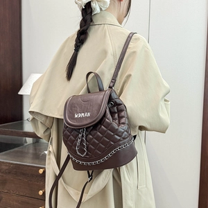 Close-up of brown quilted leather backpack featuring diamond stitching and metal chain detail