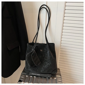 Dettaglio della borsa tote vintage nera con borsellino su una valigia d'argento