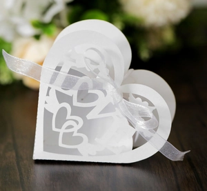 Macro shot of white laser-cut LOVE heart wedding favor box with ribbon detail