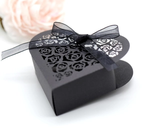 Detail of matte black heart-shaped gift box with laser-cut roses and ribbon bow