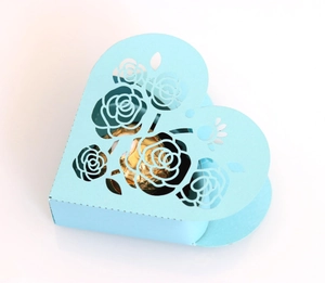 Detail showing laser-cut rose patterns on a light blue heart-shaped paper candy box