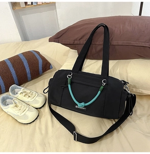 Detailansicht der schwarzen Nylon Reisetasche mit blauem Seil auf einem gemütlichen Bett