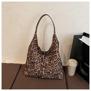 Detail of large leopard print tote bag with brown straps on a sofa in a casual setting