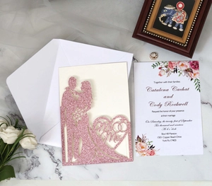 Macro shot of laser-cut pink glitter wedding invitation with Mr & Mrs heart pattern