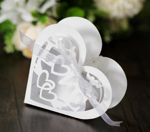 Detail of white heart-shaped candy box with laser-cut LOVE text and ribbon bow