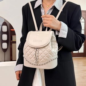 Detail of cream quilted PU leather backpack with WOMAN logo and metal chain on model