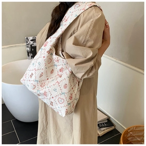 Detail of white quilted tote bag featuring pink bear patterns and wide shoulder strap